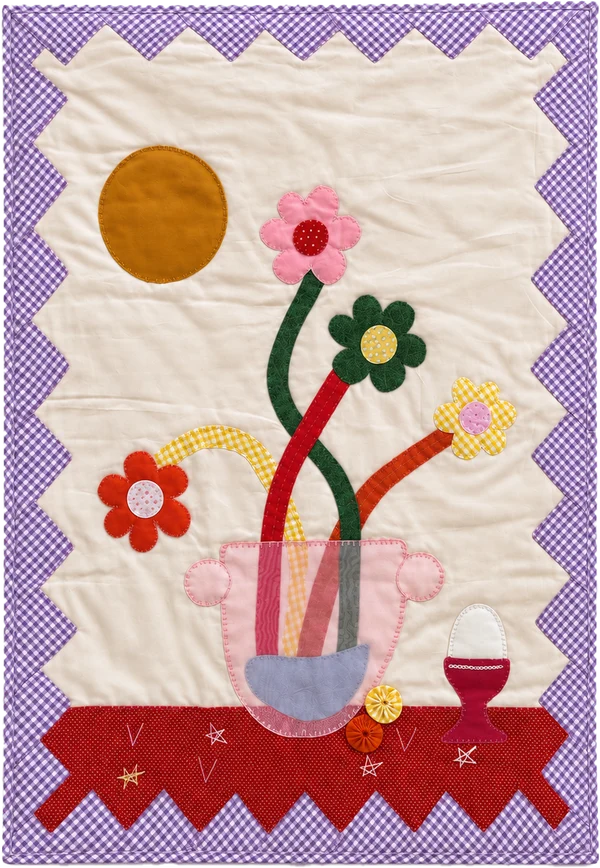 Quilt with colorful flowers in a vase, a red cup and a lilac zigzag border.